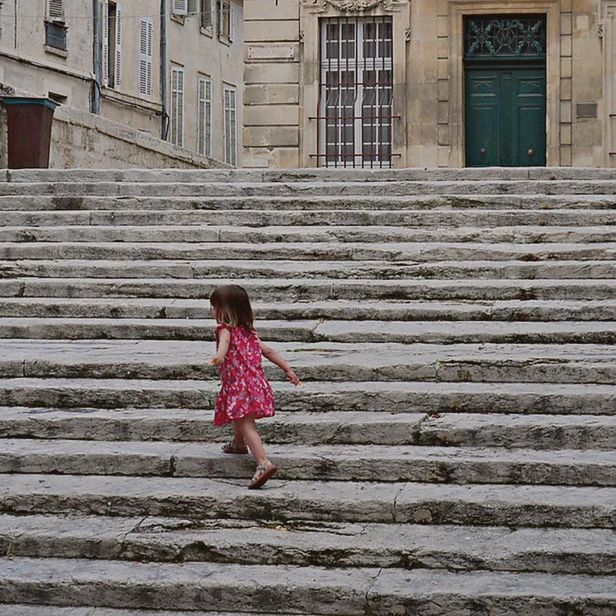 Enfant montant un escalier de pierre dans une rue d'Arles